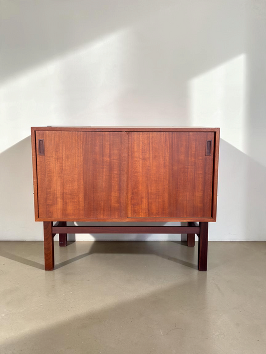 tessvintage Deens teak dressoir met twee schuifdeuren en een donkerhouten H-frame onderstel in een strak design