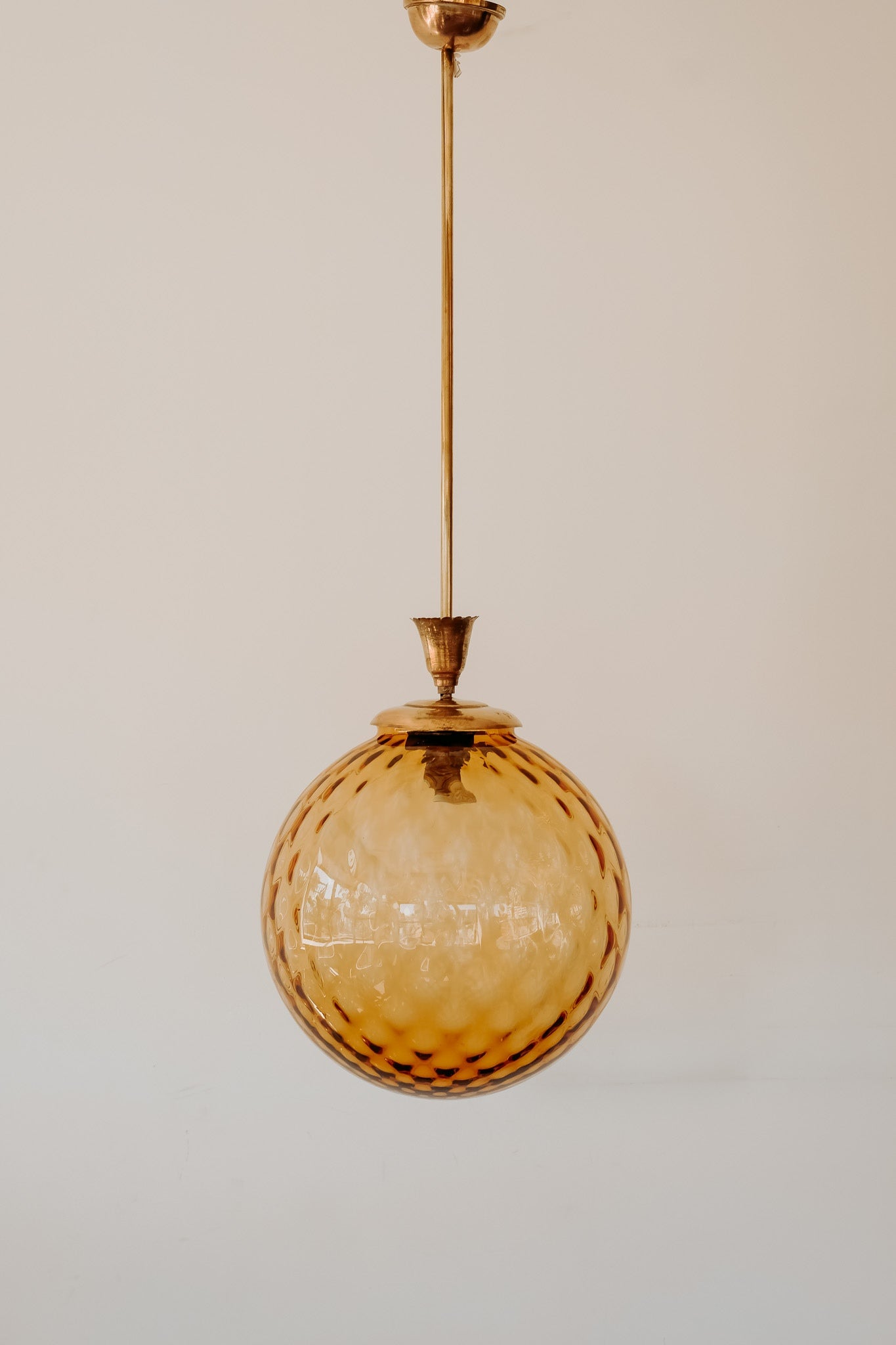 Messing hanglamp met ronde oranje glazen kap en swirl structuur