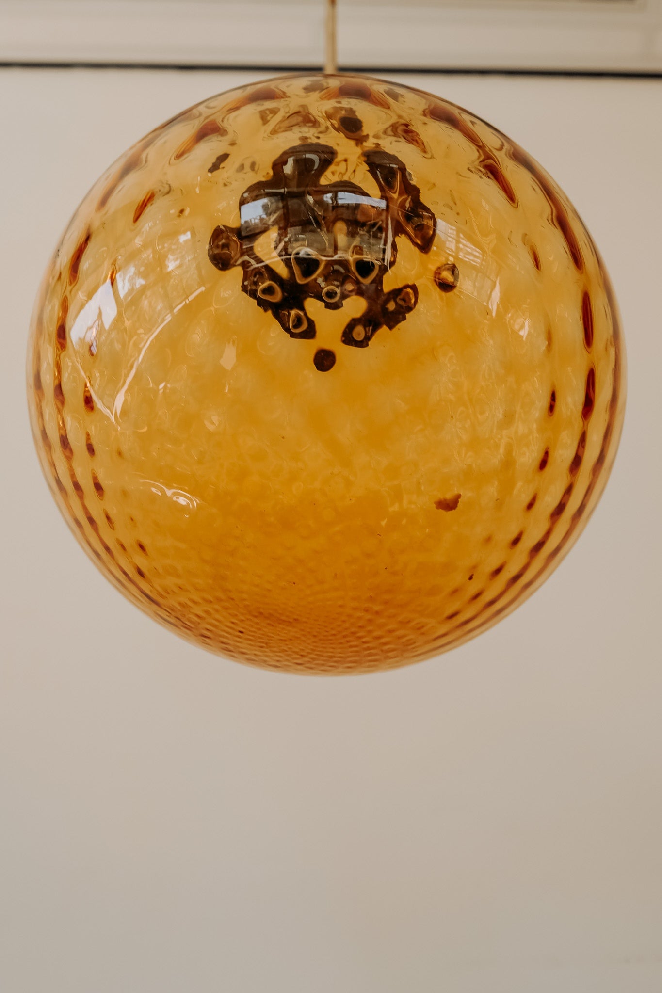 Messing hanglamp met ronde oranje glazen kap en swirl structuur