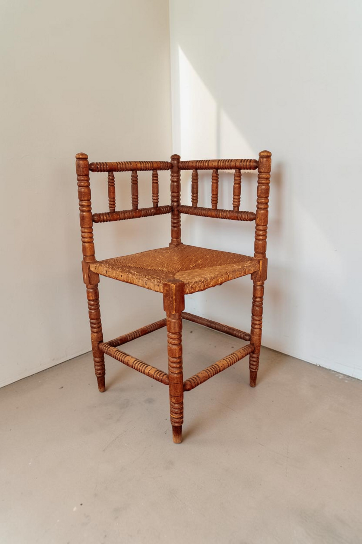 tessvintage vintage houten bobbin hoekstoel met een gevlochten rieten zitting in een klassieke stijl