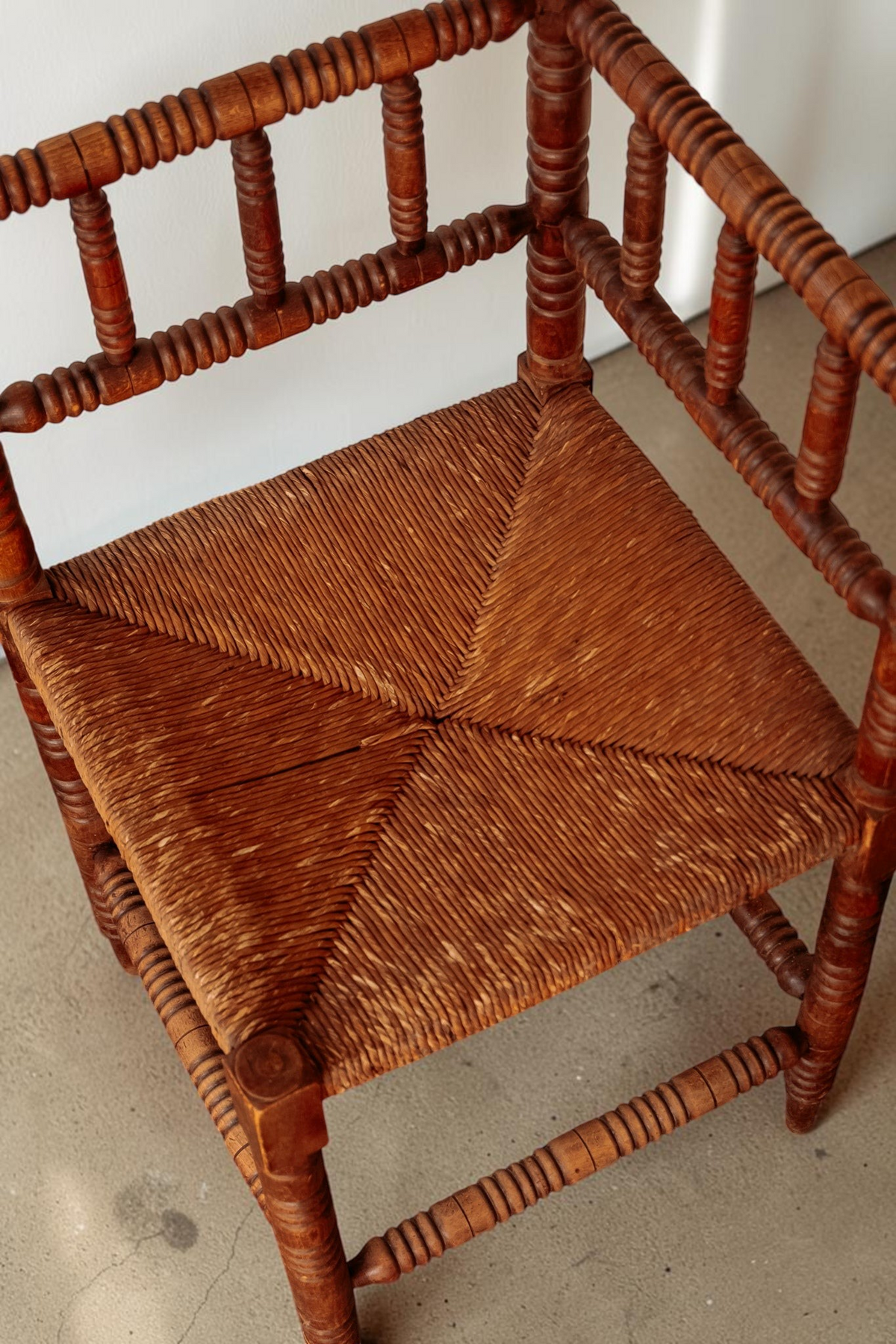 tessvintage massief houten bobbin hoekstoel met een gevlochten rieten zitting in een klassieke stijl