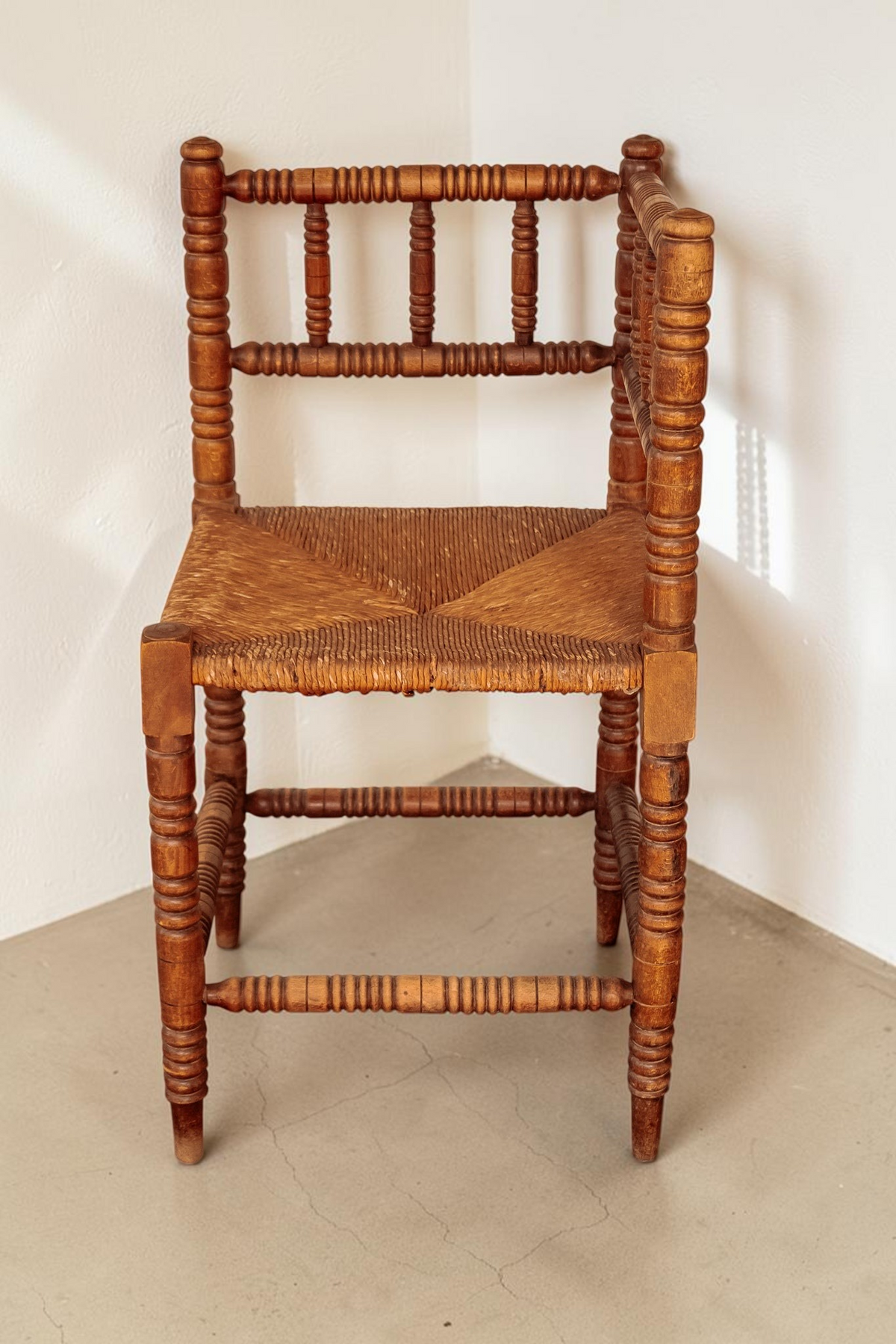 tessvintage massief houten bobbin hoekstoel met een gevlochten rieten zitting in een vintage stijl