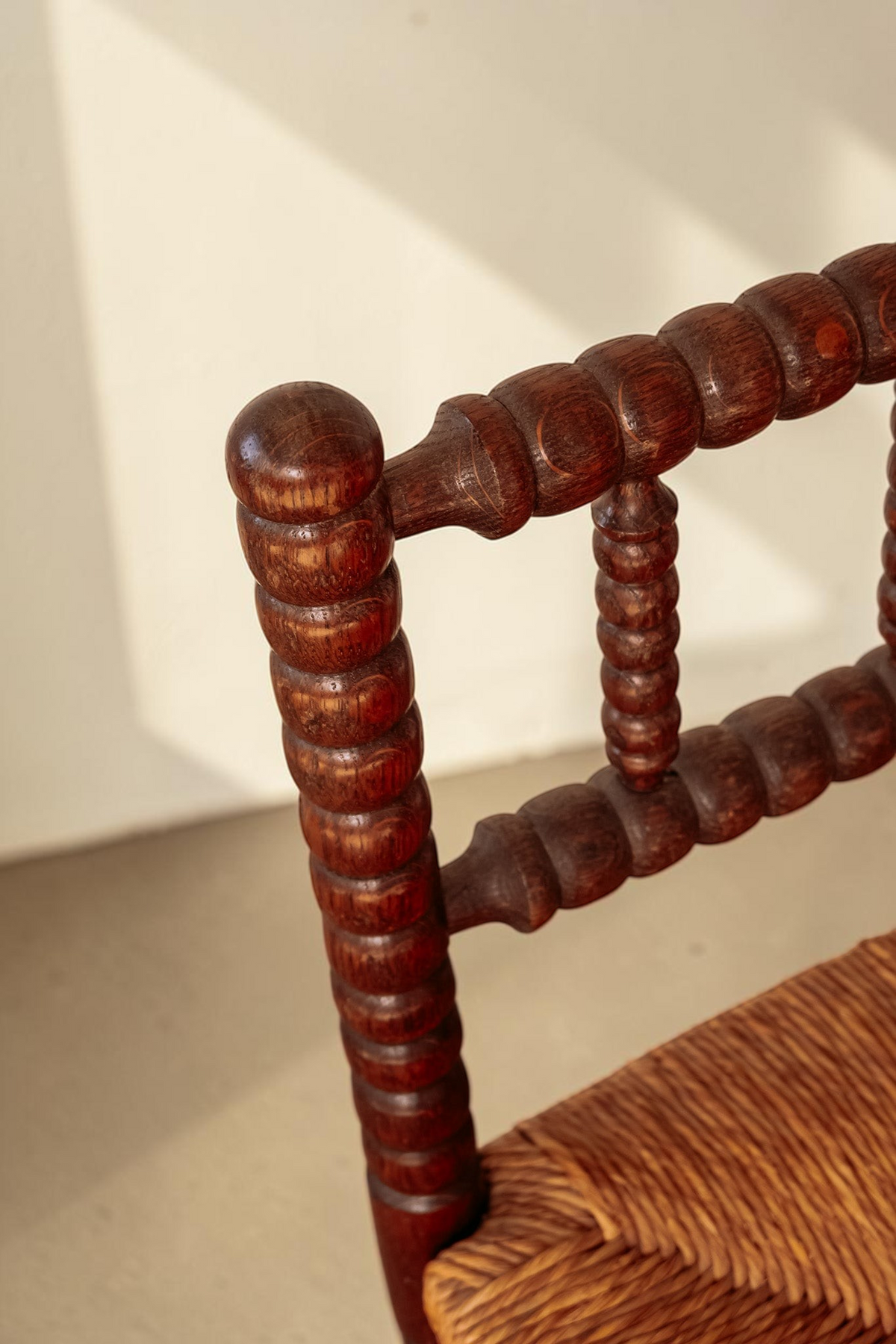 tessvintage vintage hoekstoel van donker hout met bobbin details en een gevlochten rieten zitting