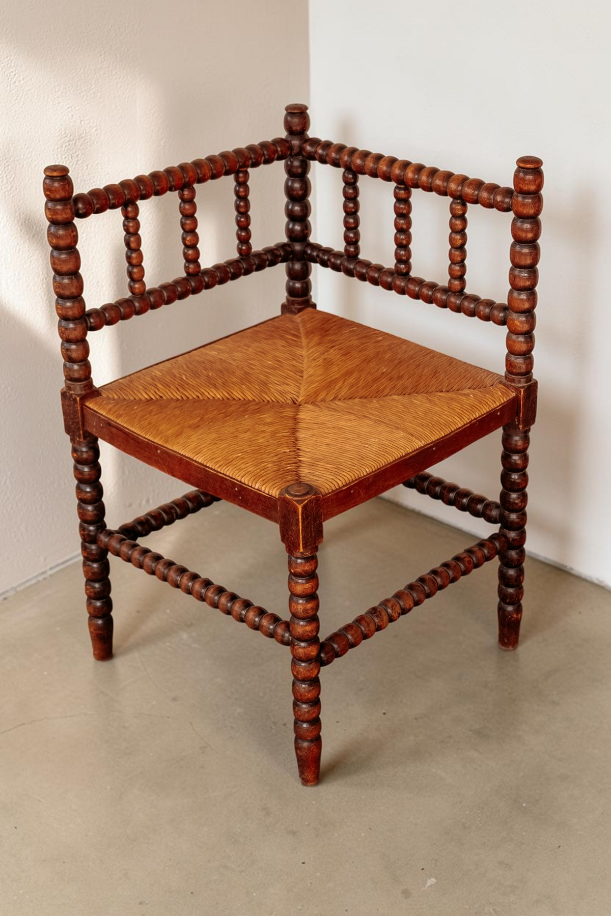 tessvintage vintage houten hoekstoel met bobbin details en een gevlochten rieten zitting voor in de hal