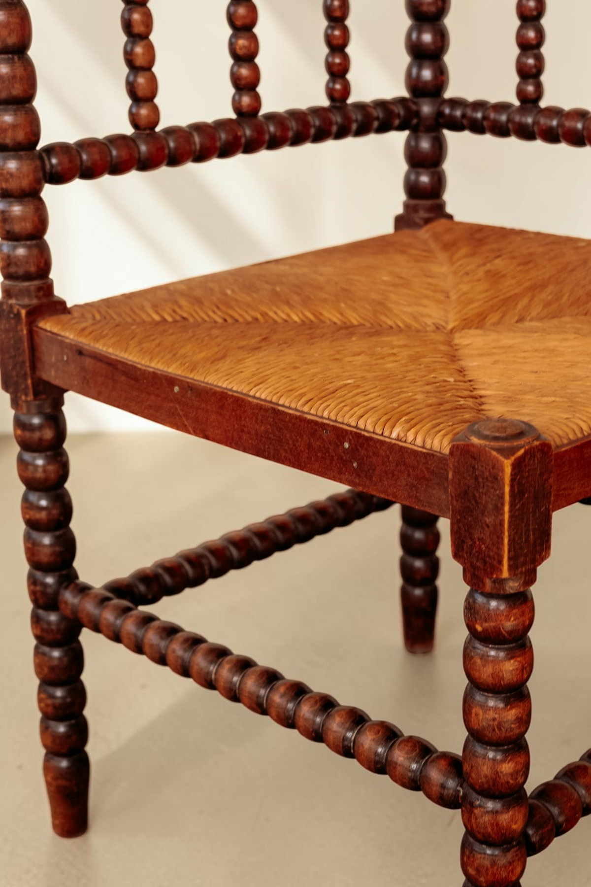 tessvintage vintage hoekstoel van massief hout met karakteristieke bobbin details en een gevlochten rieten zitting