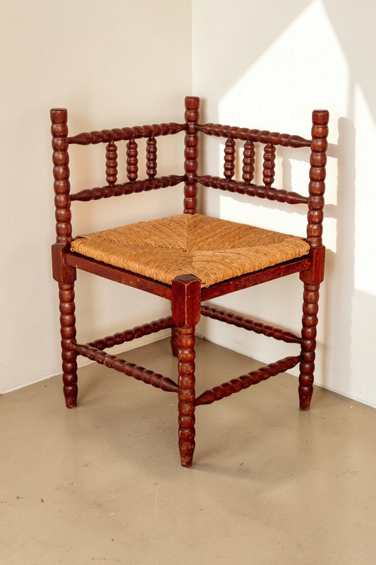 Antieke tessvintage hoekstoel van massief hout met bobbin details en een gevlochten rieten zitting