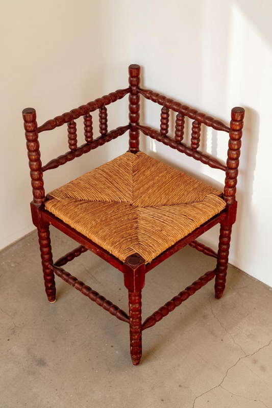 Antieke tessvintage bobbin hoekstoel van massief hout met een gevlochten rieten zitting voor in de hal of slaapkamer.