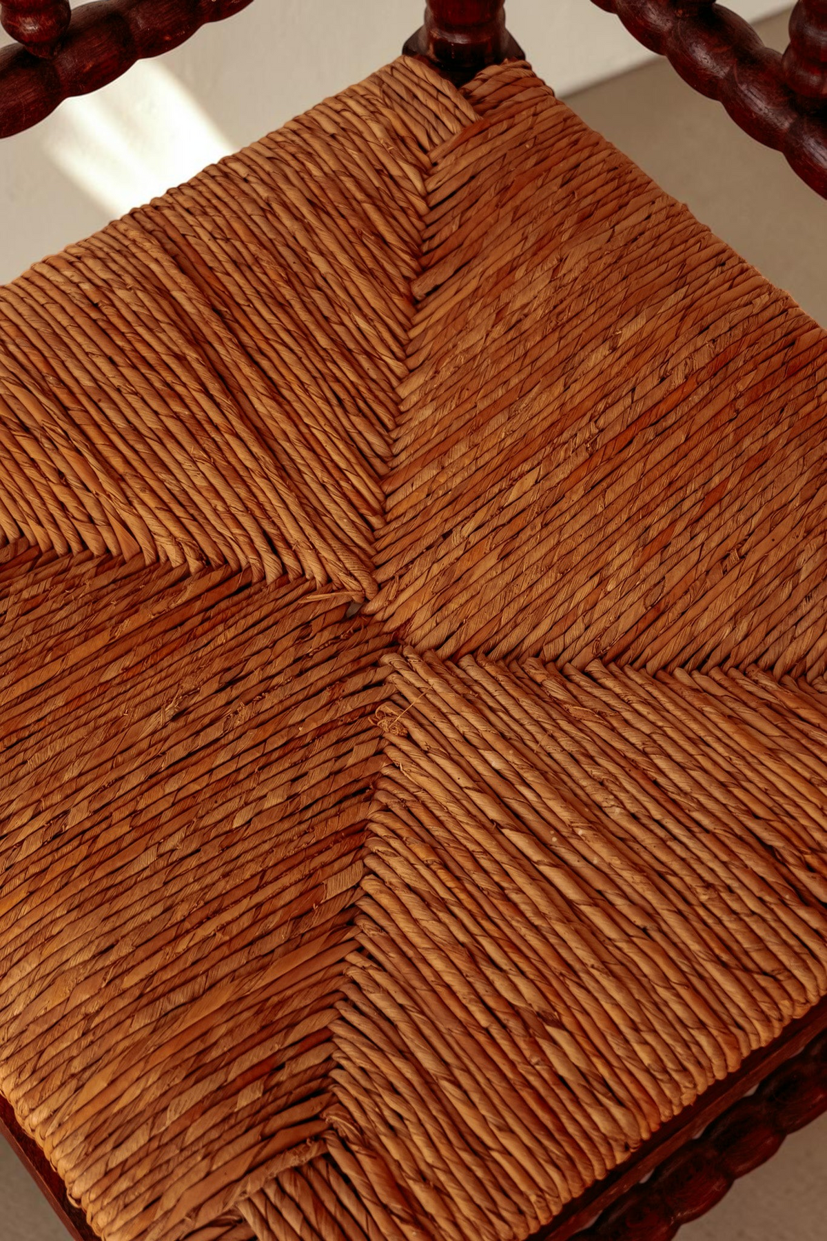 Close-up van de gevlochten rieten zitting van een antieke tessvintage bobbin hoekstoel van massief hout.