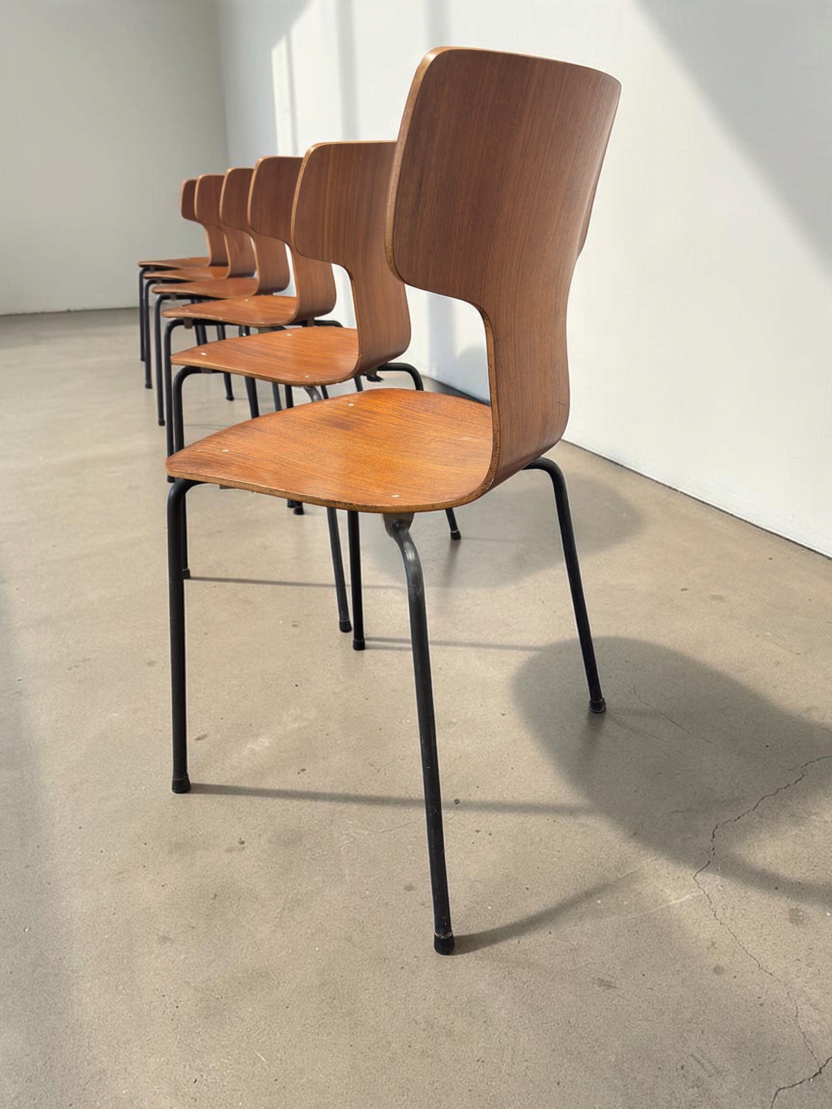 Set van zes vintage tessvintage Arne Jacobsen model 3103 T-stoelen met gebogen teakfineer en zwarte metalen poten.