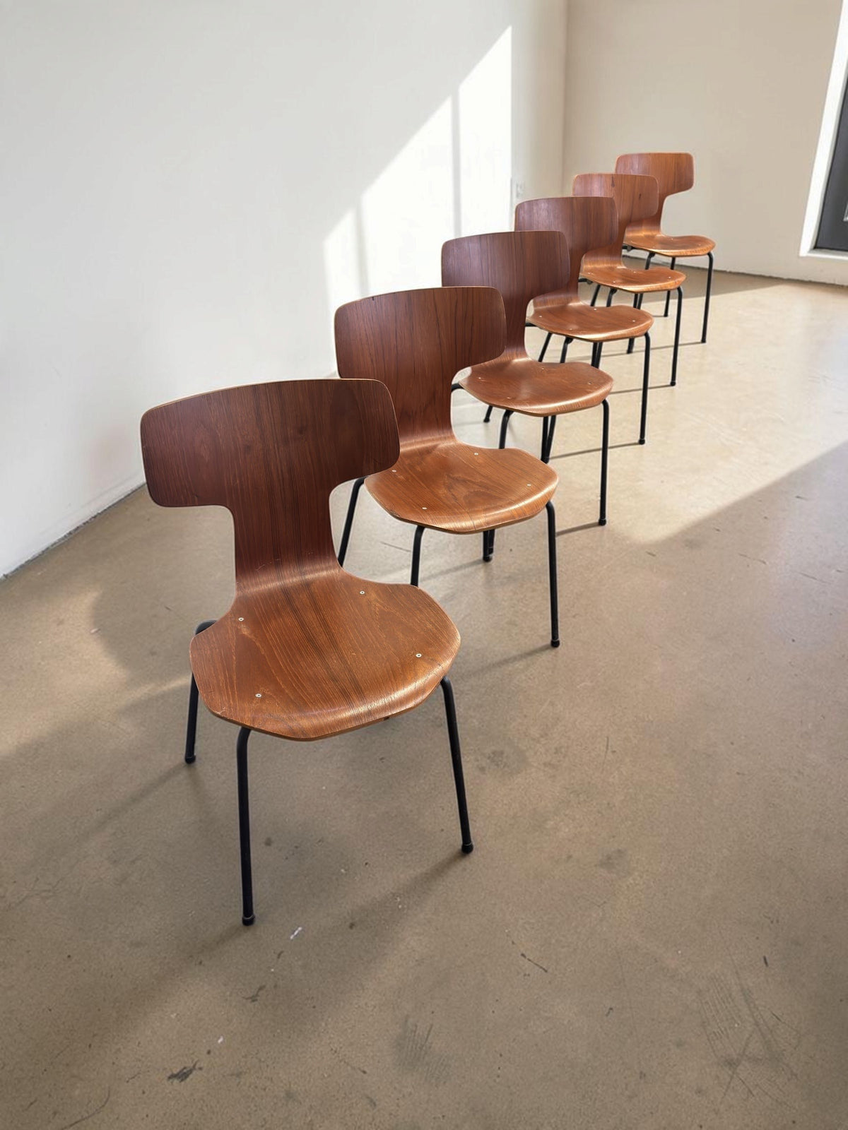 Set van zes vintage tessvintage Arne Jacobsen model 3103 T-stoelen met gebogen teakfineer en zwarte metalen poten.
