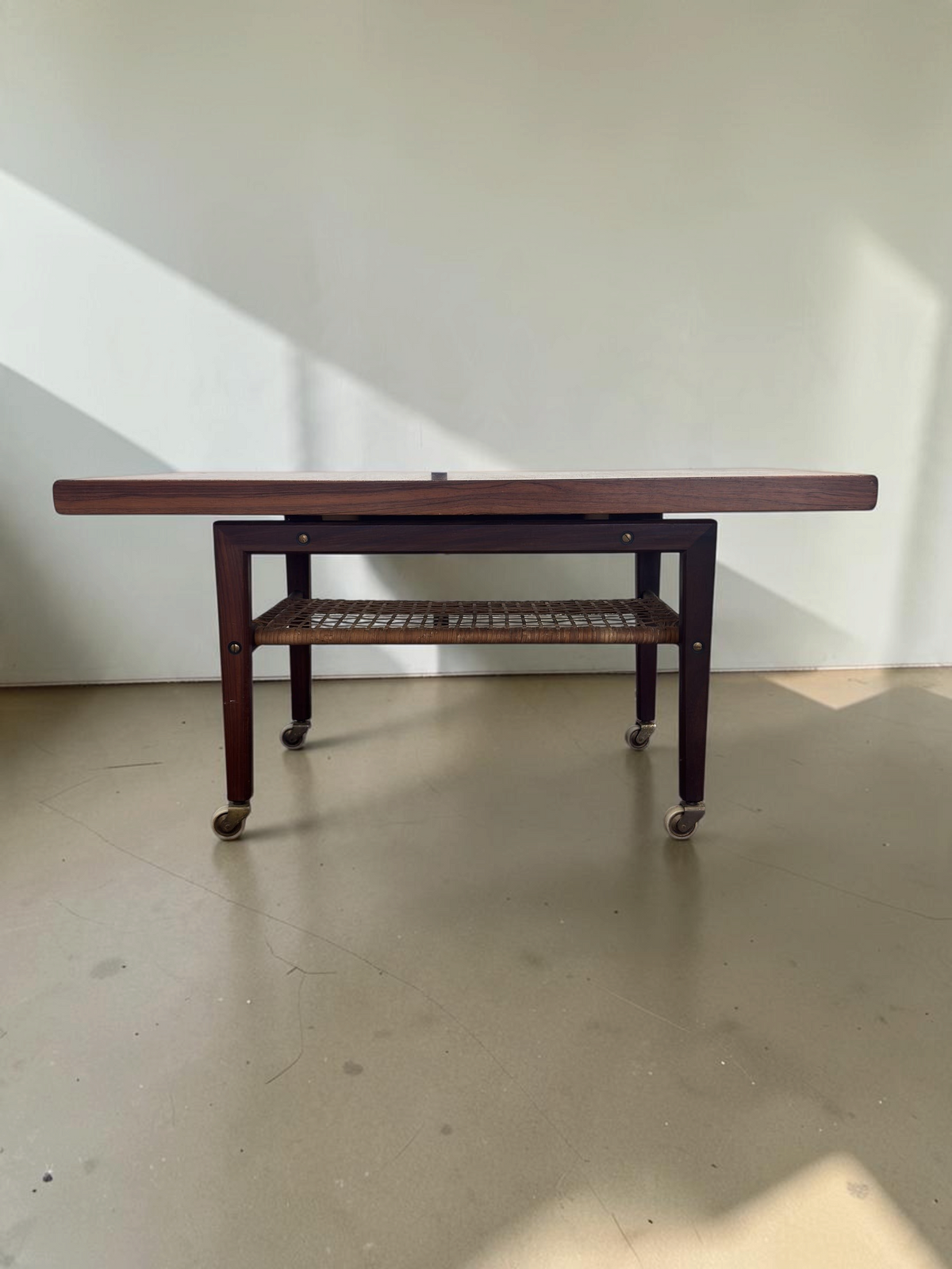 tessvintage Scandinavische salontafel van pallisanderhout met rotan lectuurrek en messing wieltjes uit de jaren 60
