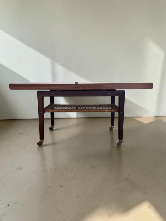 tessvintage Scandinavische salontafel van pallisanderhout met rotan lectuurrek en messing wieltjes uit de jaren 60