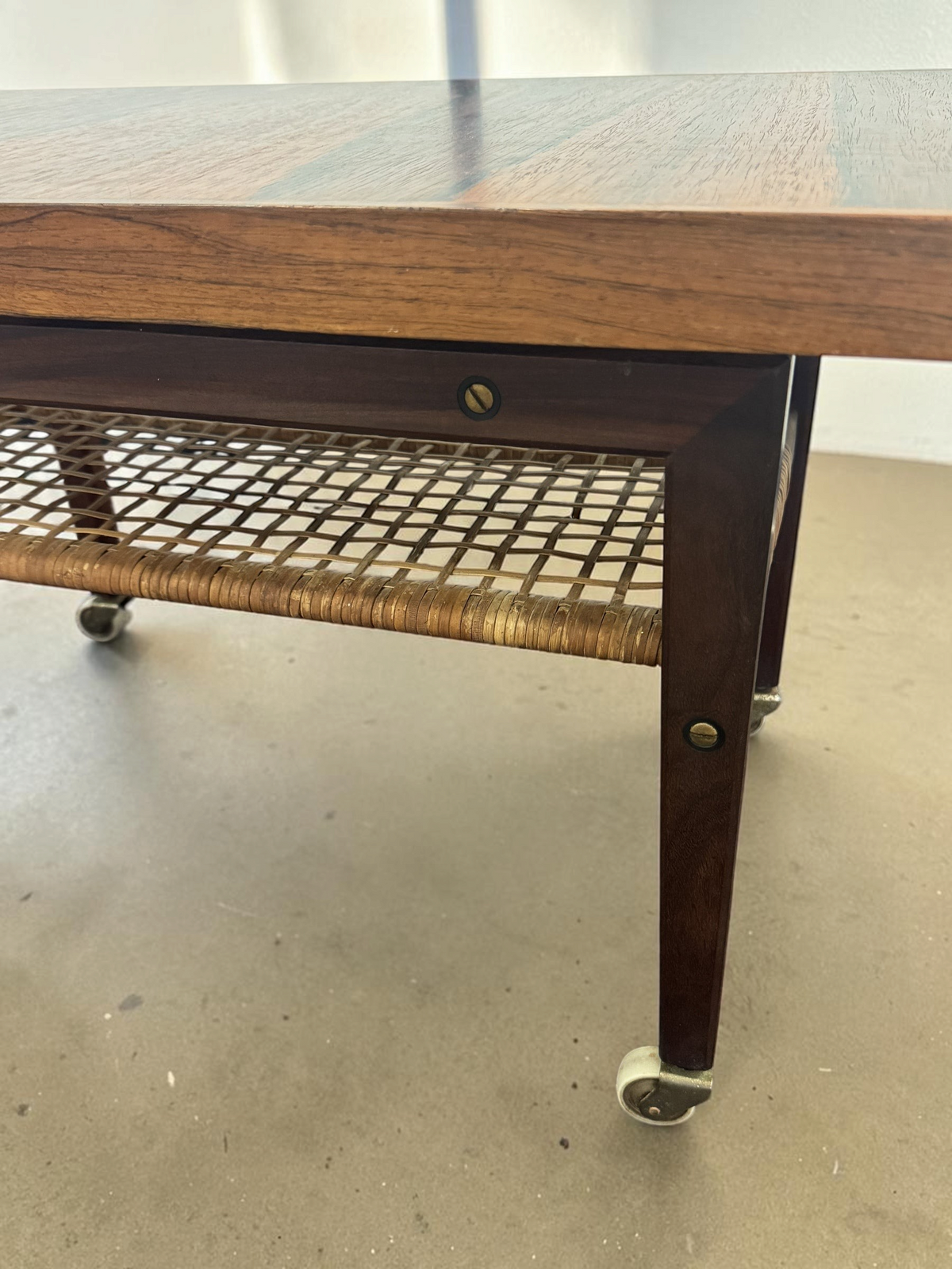 tessvintage Scandinavische salontafel van pallisanderhout met rotan lectuurrek en messing wieltjes