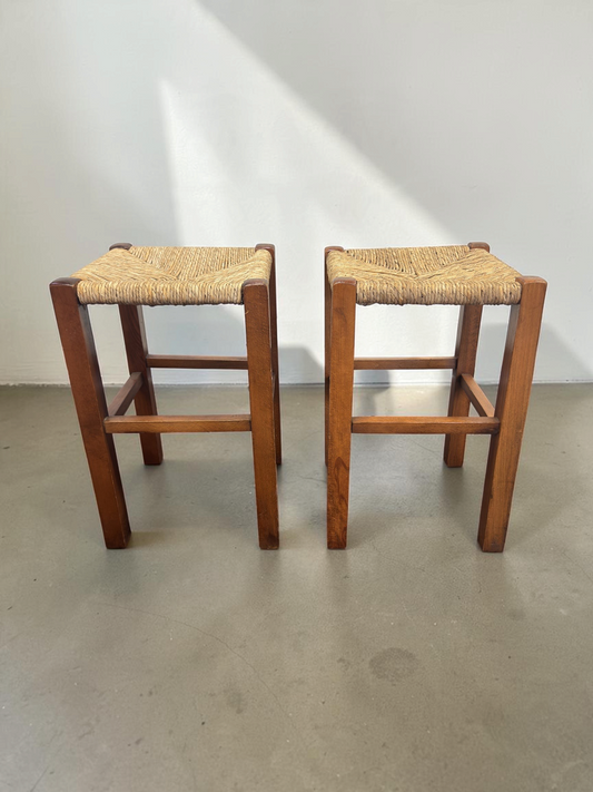 Set van twee tessvintage houten krukjes met een bruin frame en een gevlochten biezen zitting in visgraatpatroon.