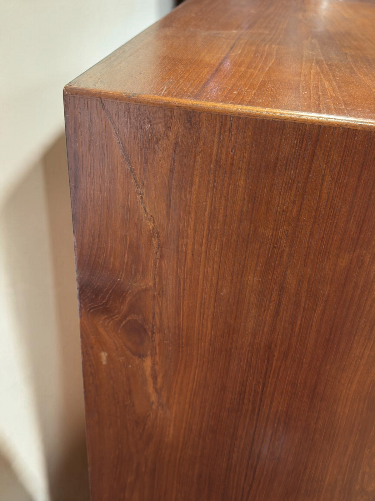 Detail van de zijkant van een tessvintage Deense teakhouten ladekast door Kai Kristiansen met zichtbare kras.