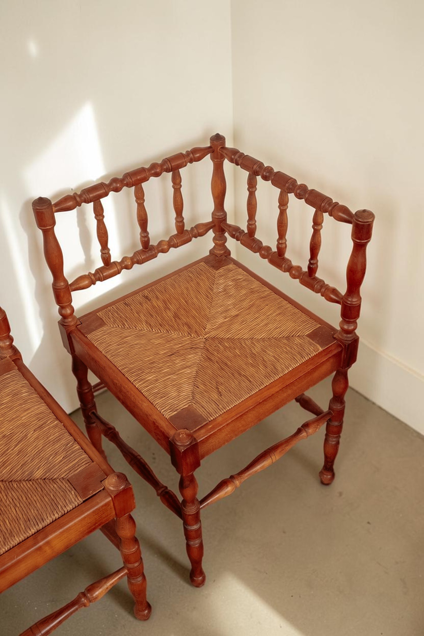 Set van twee antieke Franse tessvintage hoekstoelen met gedraaide houten spijlen en een gevlochten biezen zitting.