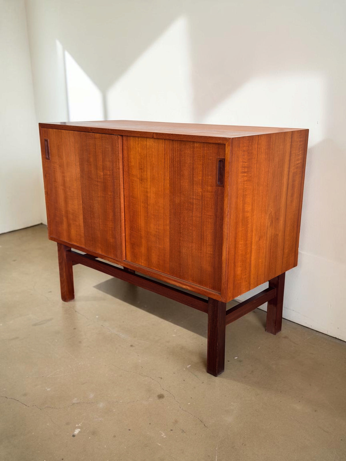 tessvintage Deens teak dressoir met schuifdeuren en een donker houten H-frame onderstel in een strak vintage design