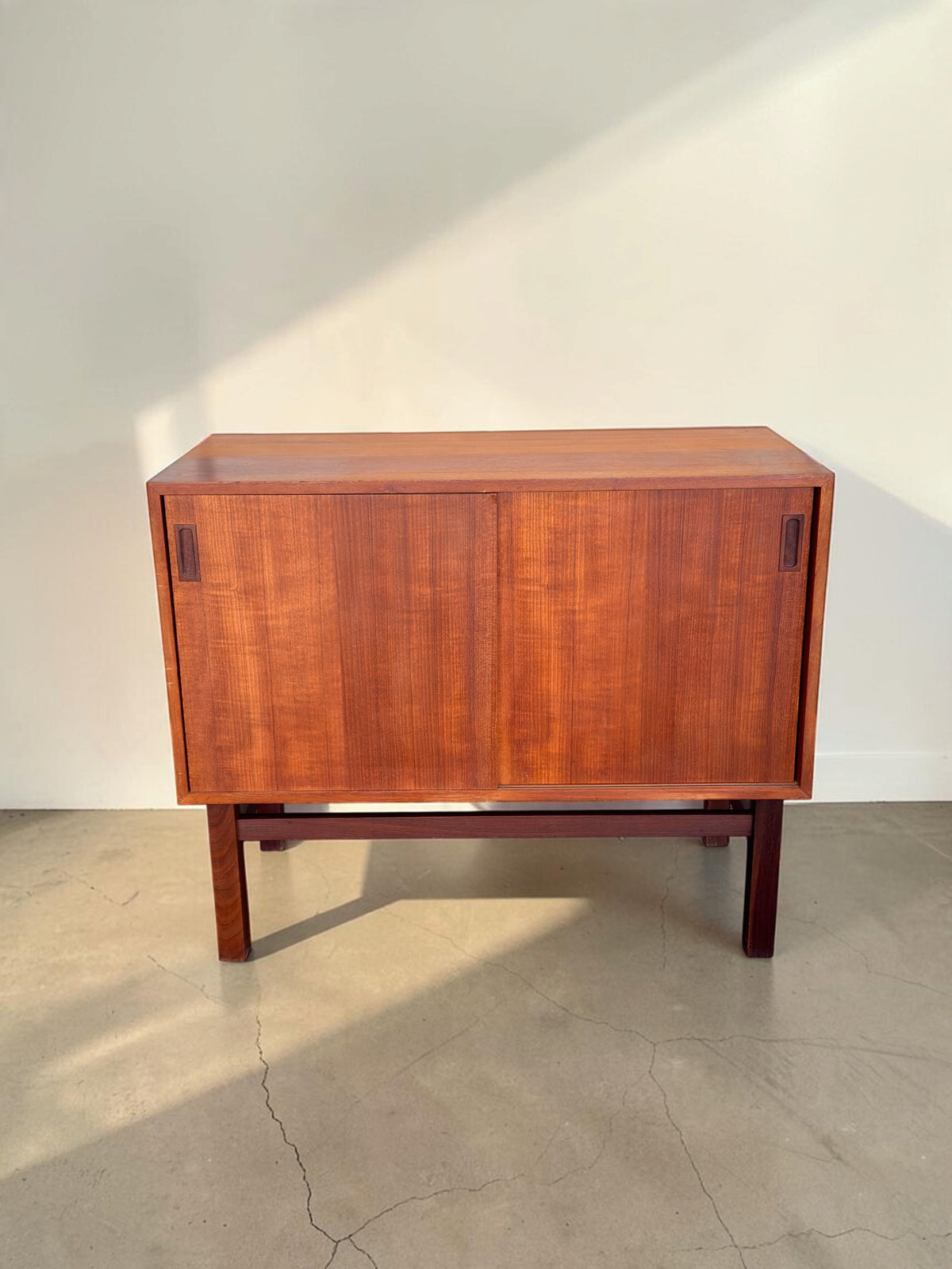 tessvintage Deens teak dressoir met schuifdeuren en donker houten H-frame onderstel in een strak vintage design
