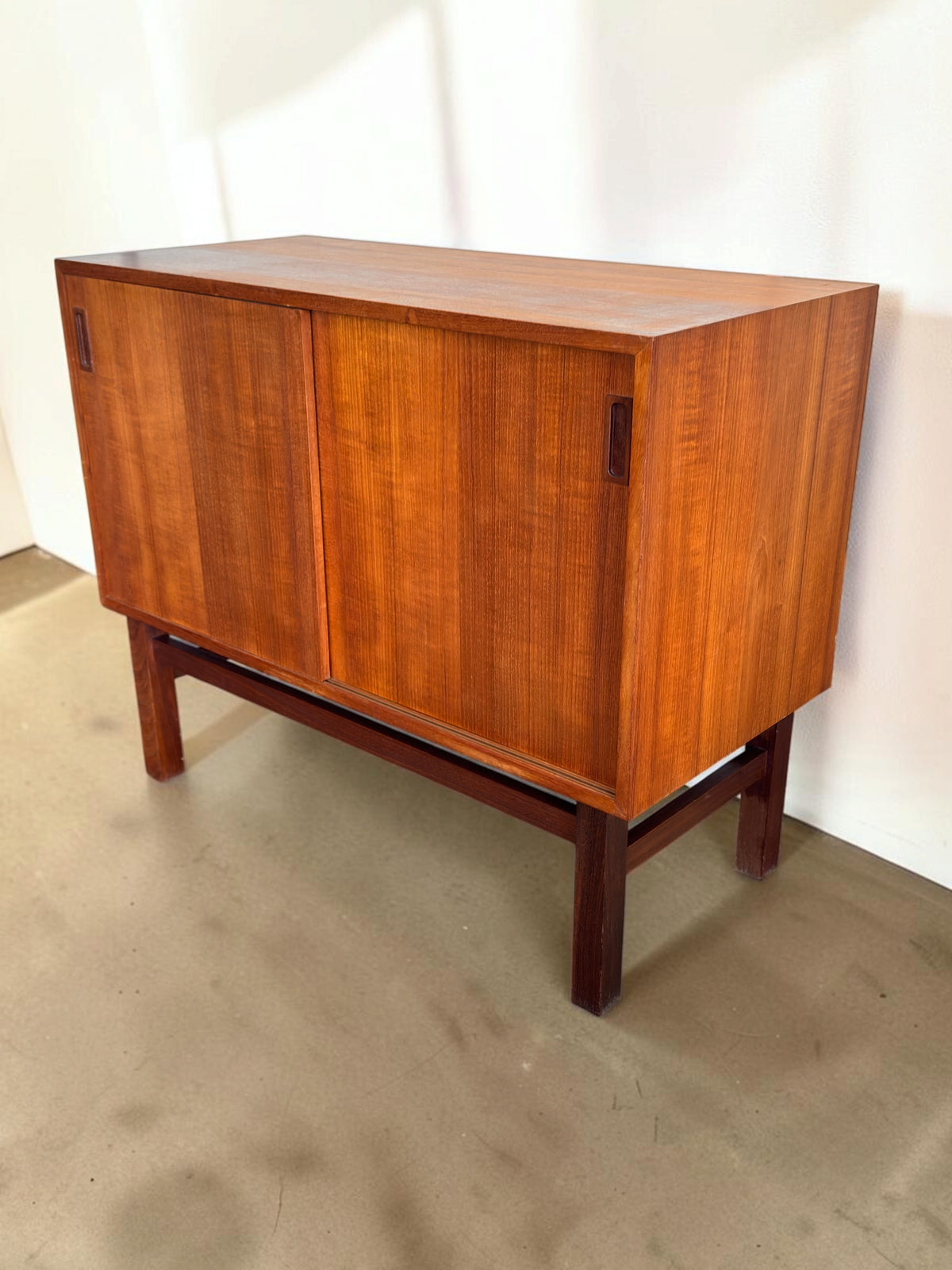 tessvintage Deens teak dressoir met schuifdeuren en een donker houten H-frame onderstel in een strak vintage design.