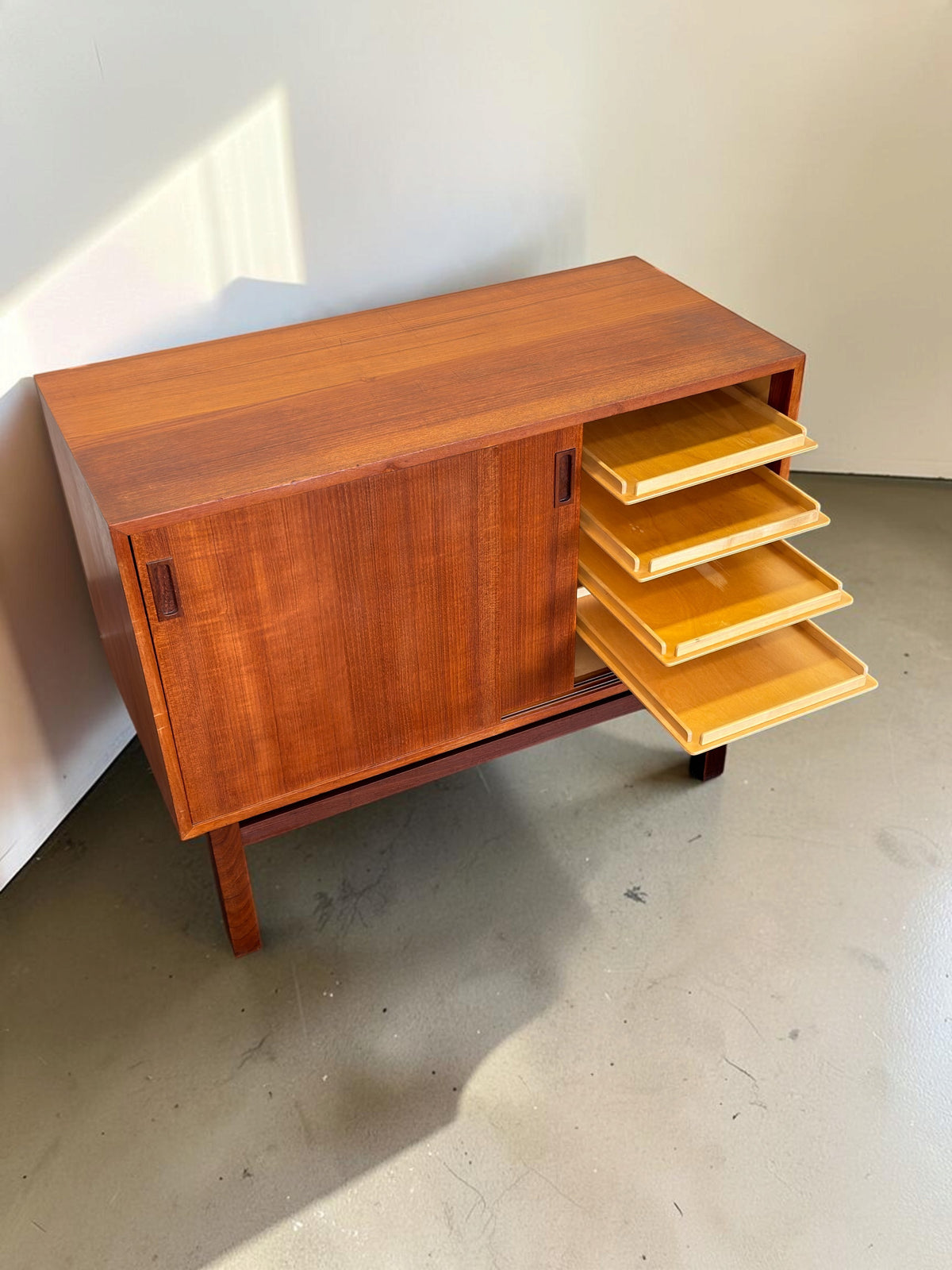 tessvintage Deens teak dressoir met schuifdeuren en vier uitschuifbare lades op een donker houten H-frame onderstel