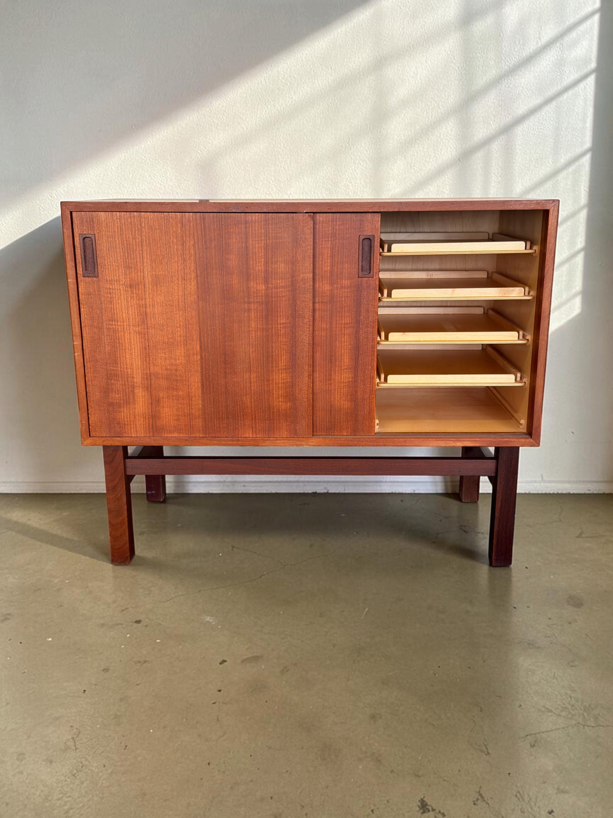 tessvintage Deens teak dressoir met schuifdeuren, vier lichte houten lades en een strak H-frame onderstel.