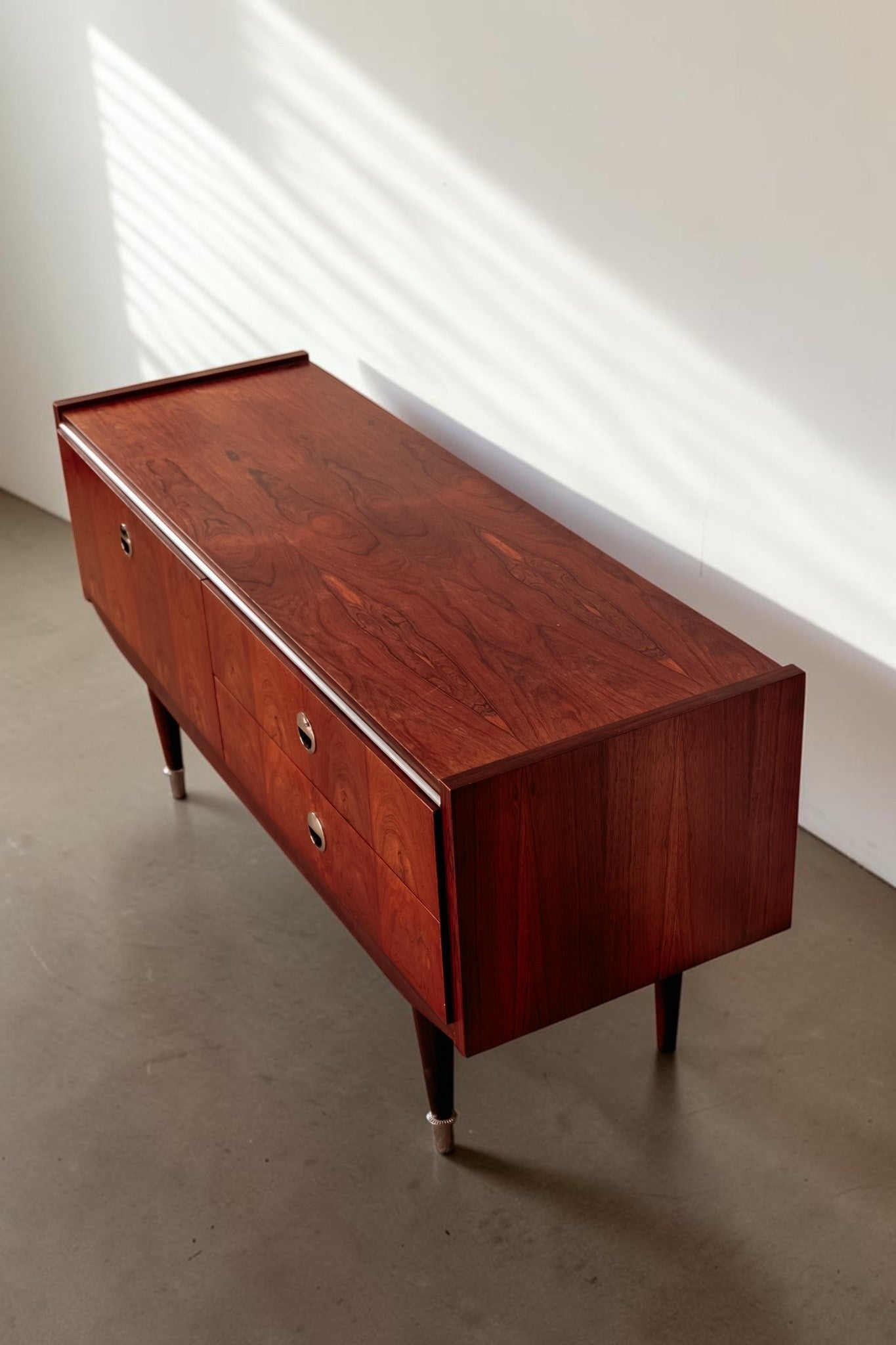 tessvintage 1960s rosewood veneer sideboard with chrome handles and tapered legs in a warm reddish-brown finish