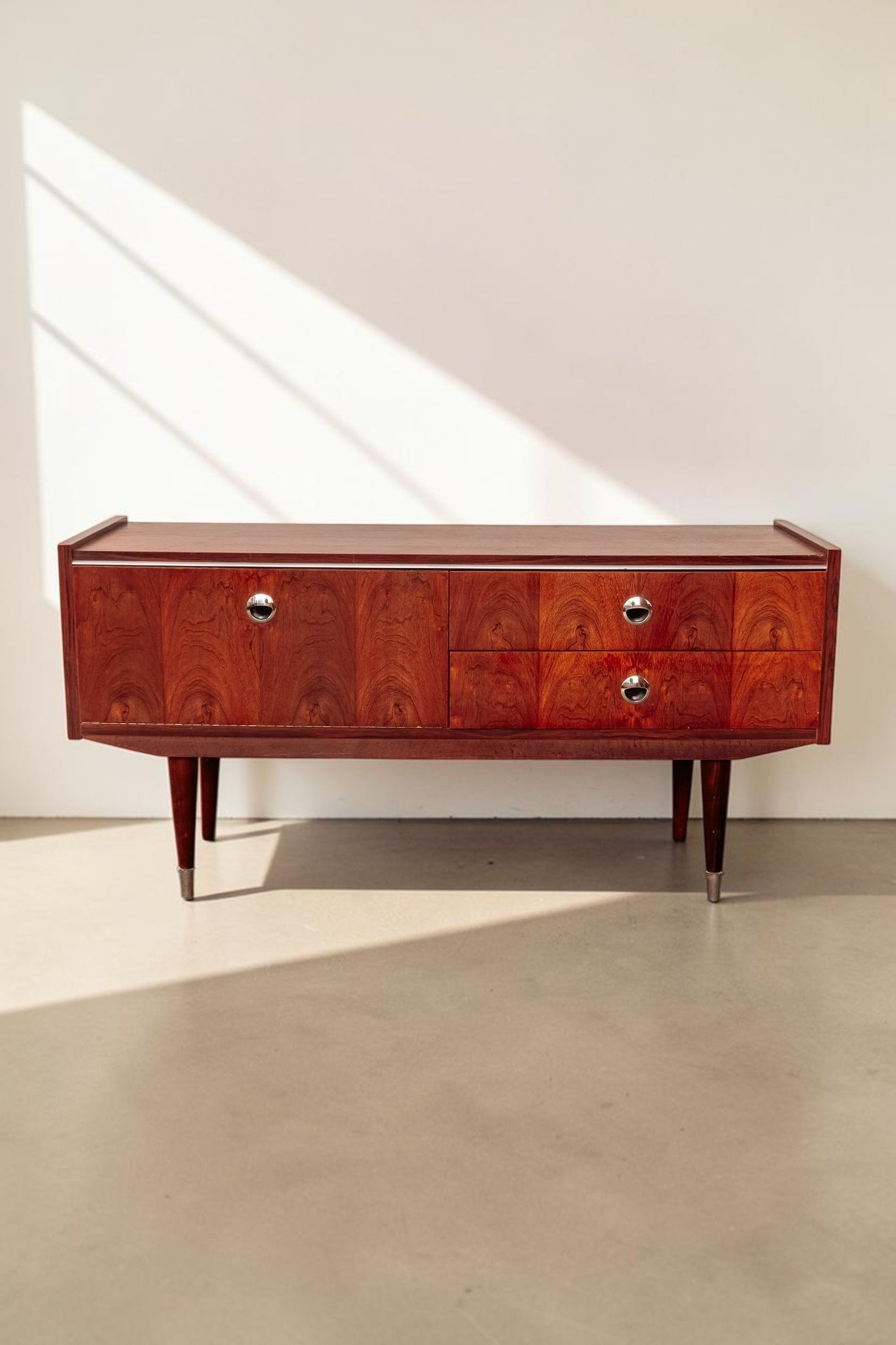 tessvintage 1960s rosewood veneer sideboard with chrome handles and tapered legs in a warm reddish-brown finish