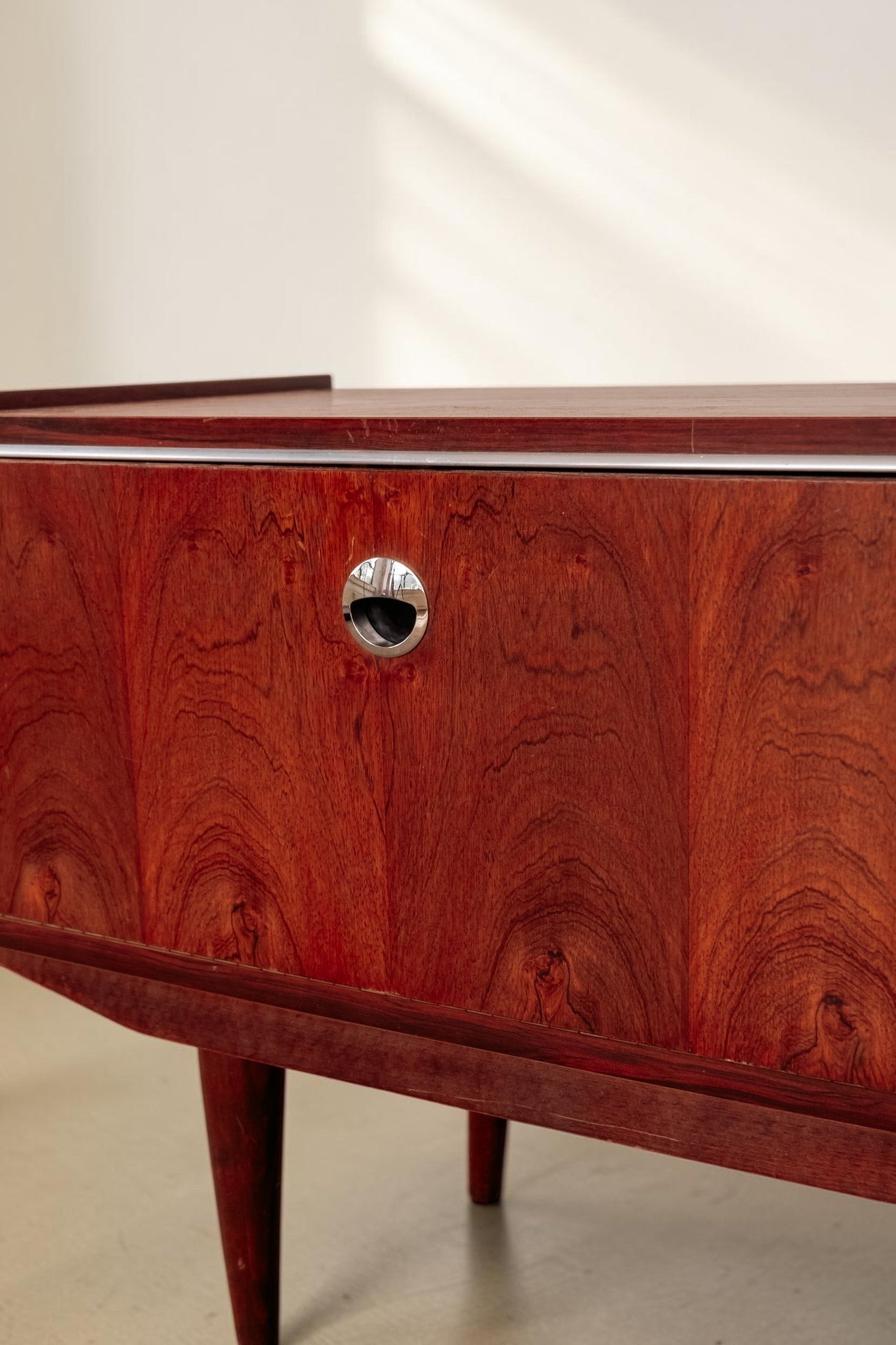 tessvintage 1960s rosewood veneer sideboard with a rich reddish-brown wood grain and a circular chrome handle