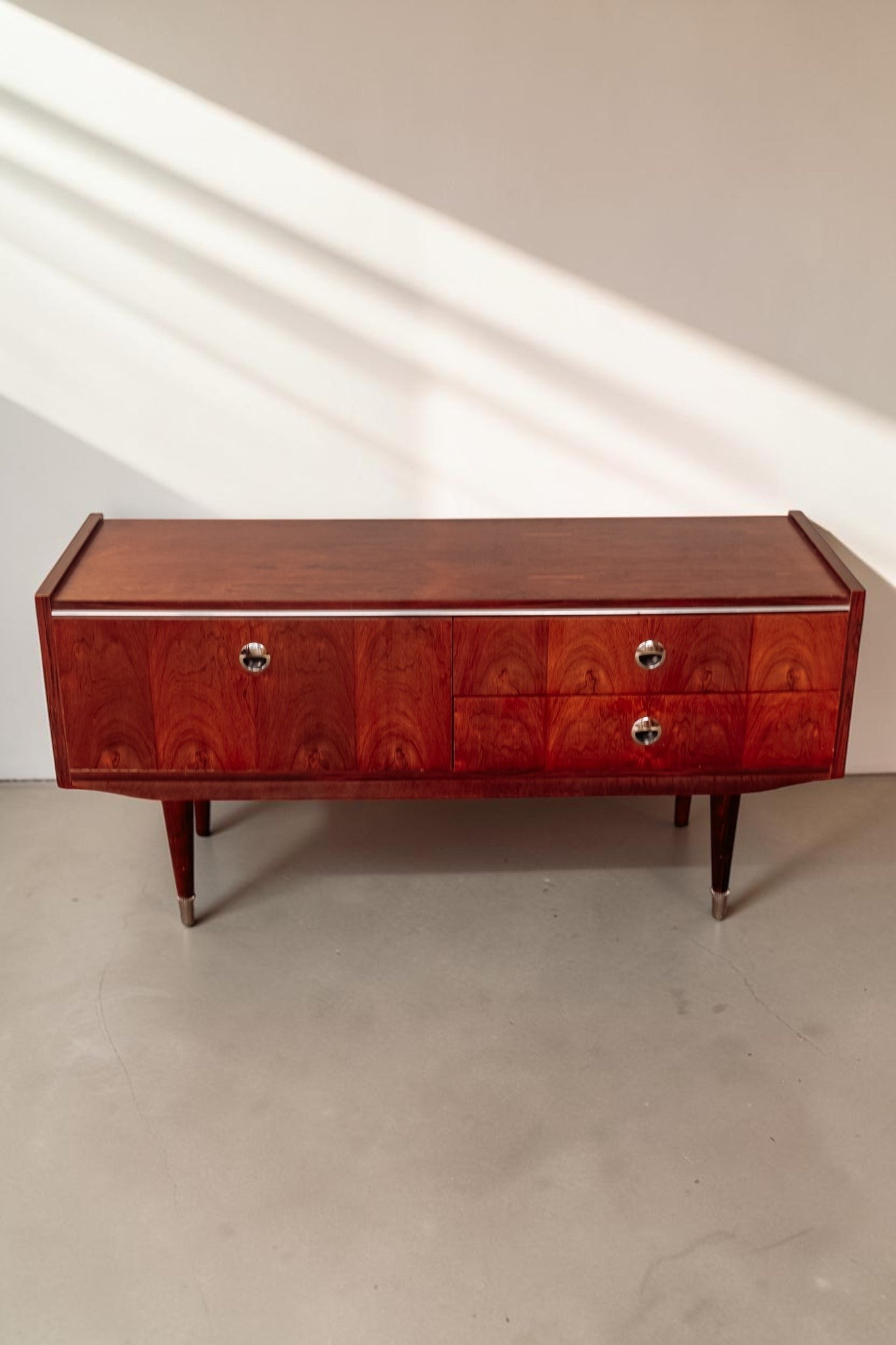 tessvintage 1960s rosewood veneer sideboard with chrome handles and tapered legs in a warm reddish-brown finish