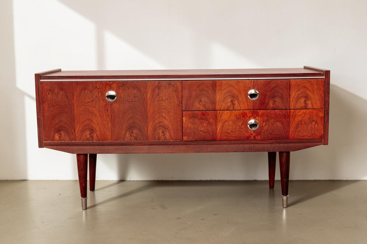 tessvintage 1960s rosewood veneer sideboard with chrome handles and tapered legs in a warm reddish-brown finish