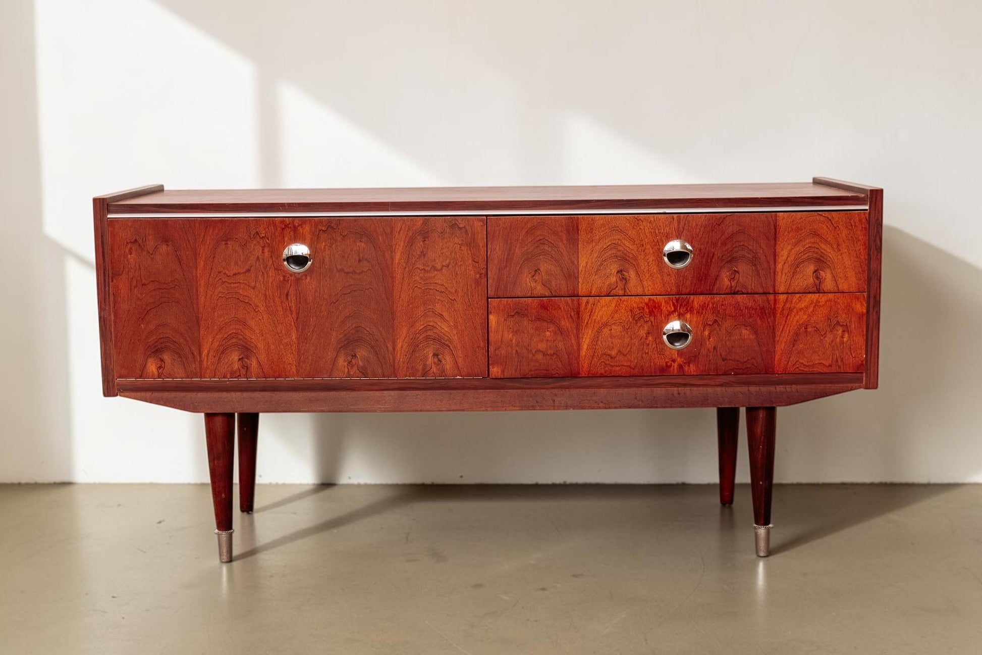 tessvintage 1960s rosewood veneer sideboard with chrome handles and tapered legs in a warm reddish-brown finish