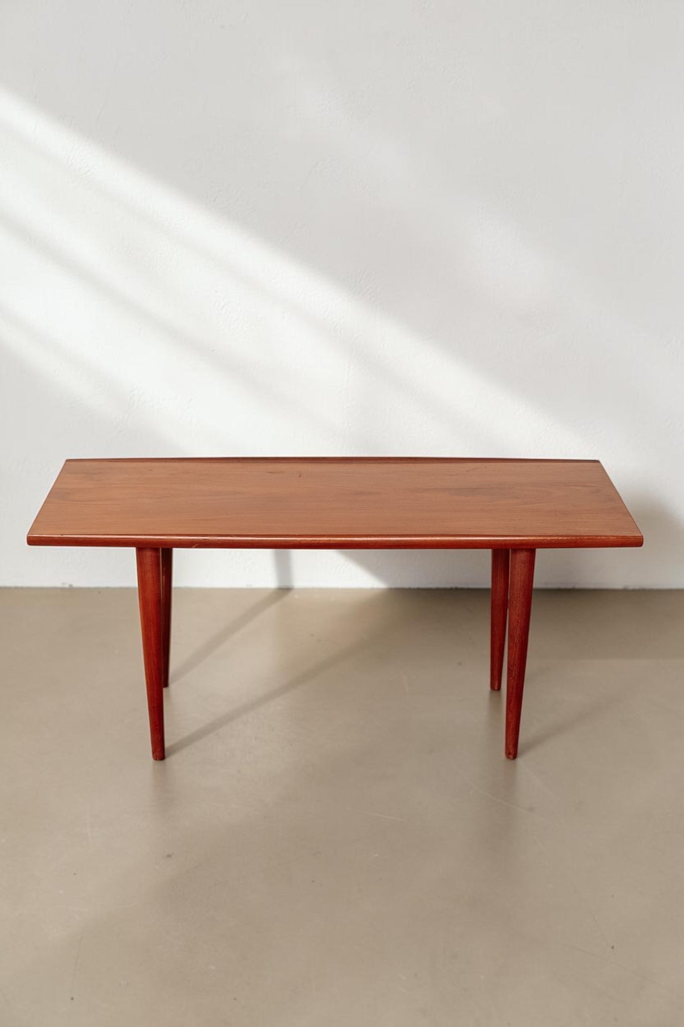 tessvintage mid-century modern teak coffee table with rounded edges and tapered legs in a warm wood finish