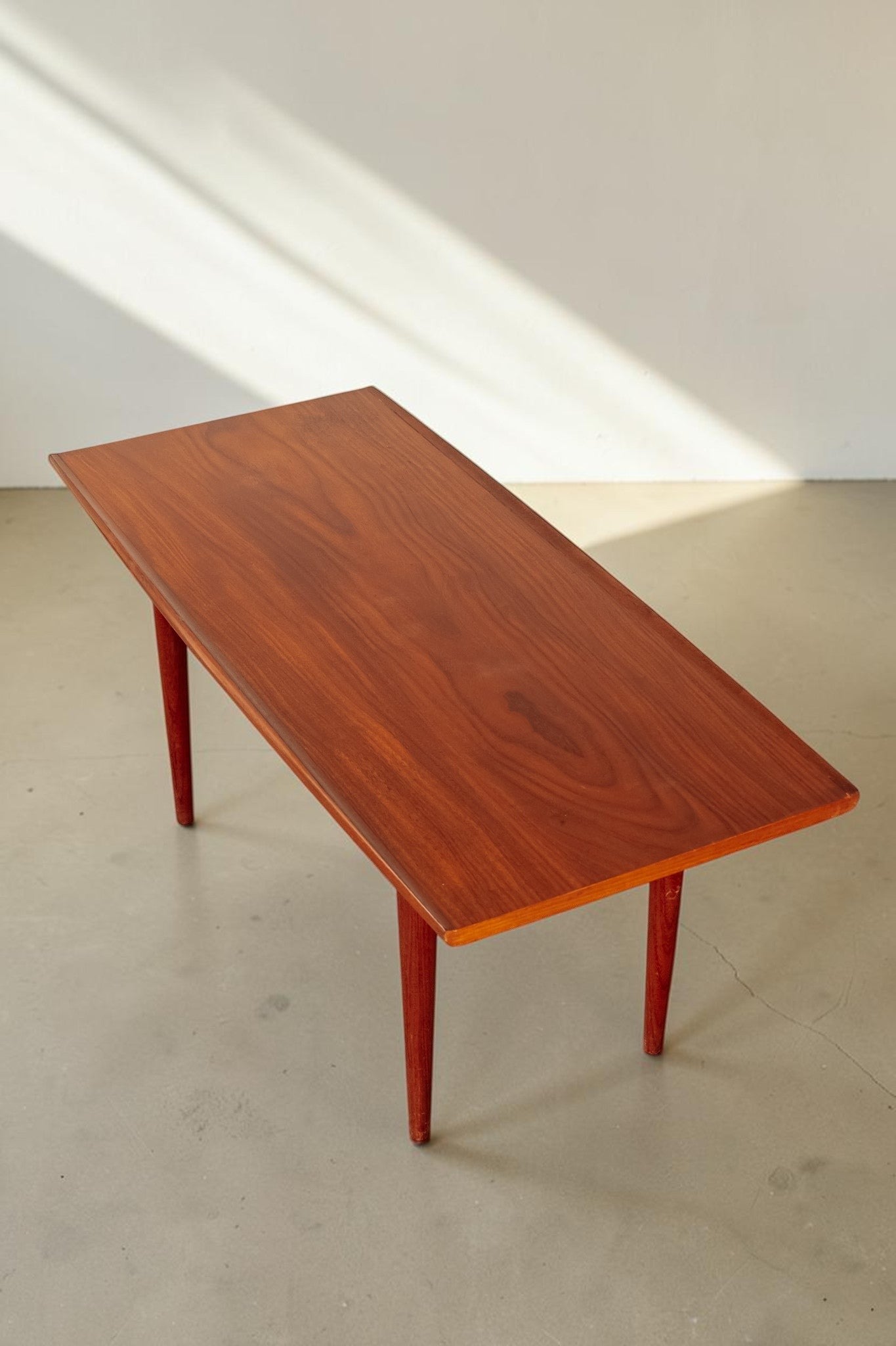 tessvintage mid-century modern teak coffee table with rounded edges and tapered legs in a warm wood finish