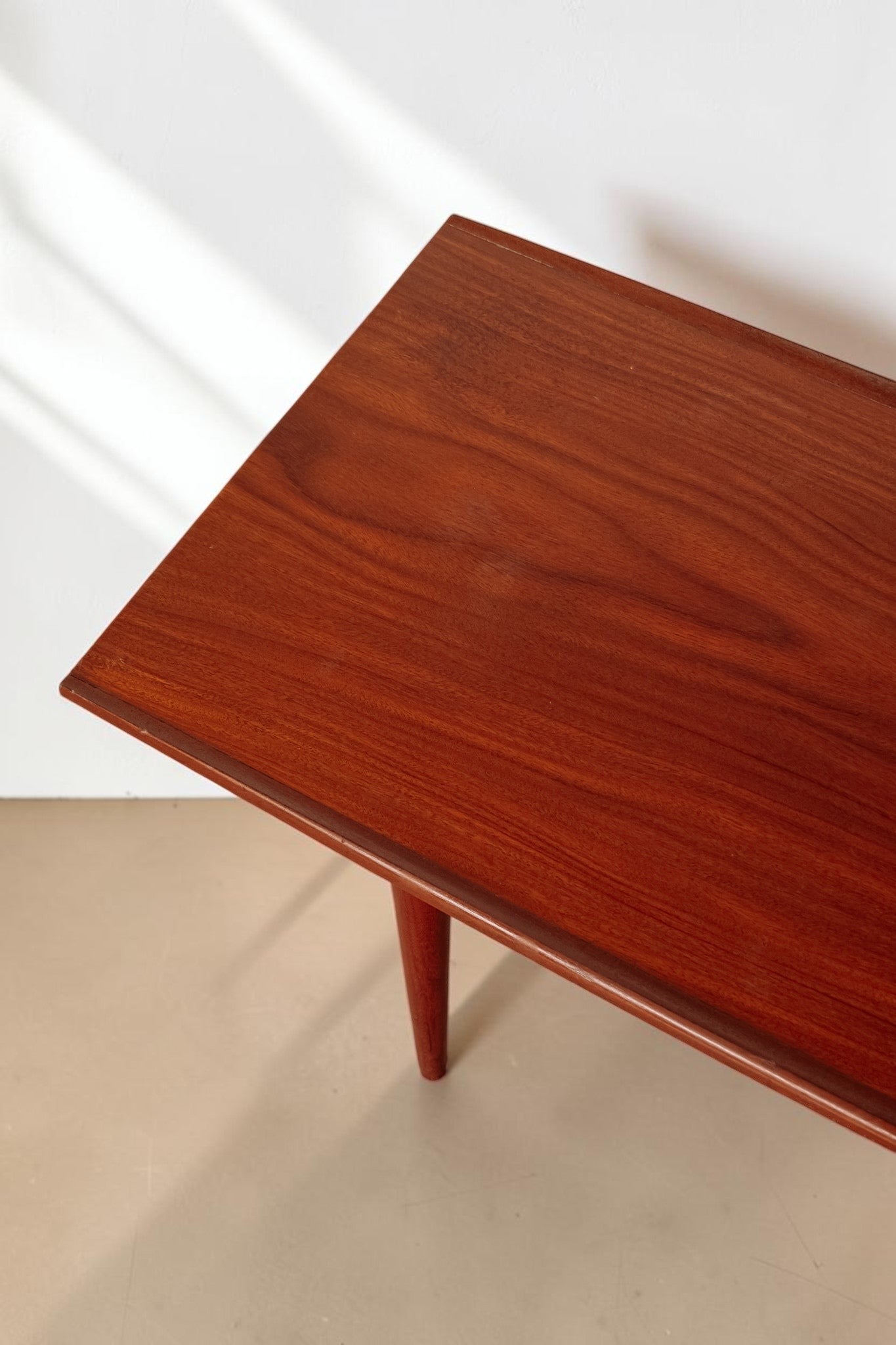 tessvintage mid-century modern teak coffee table with rounded edges and tapered legs, showing rich wood grain